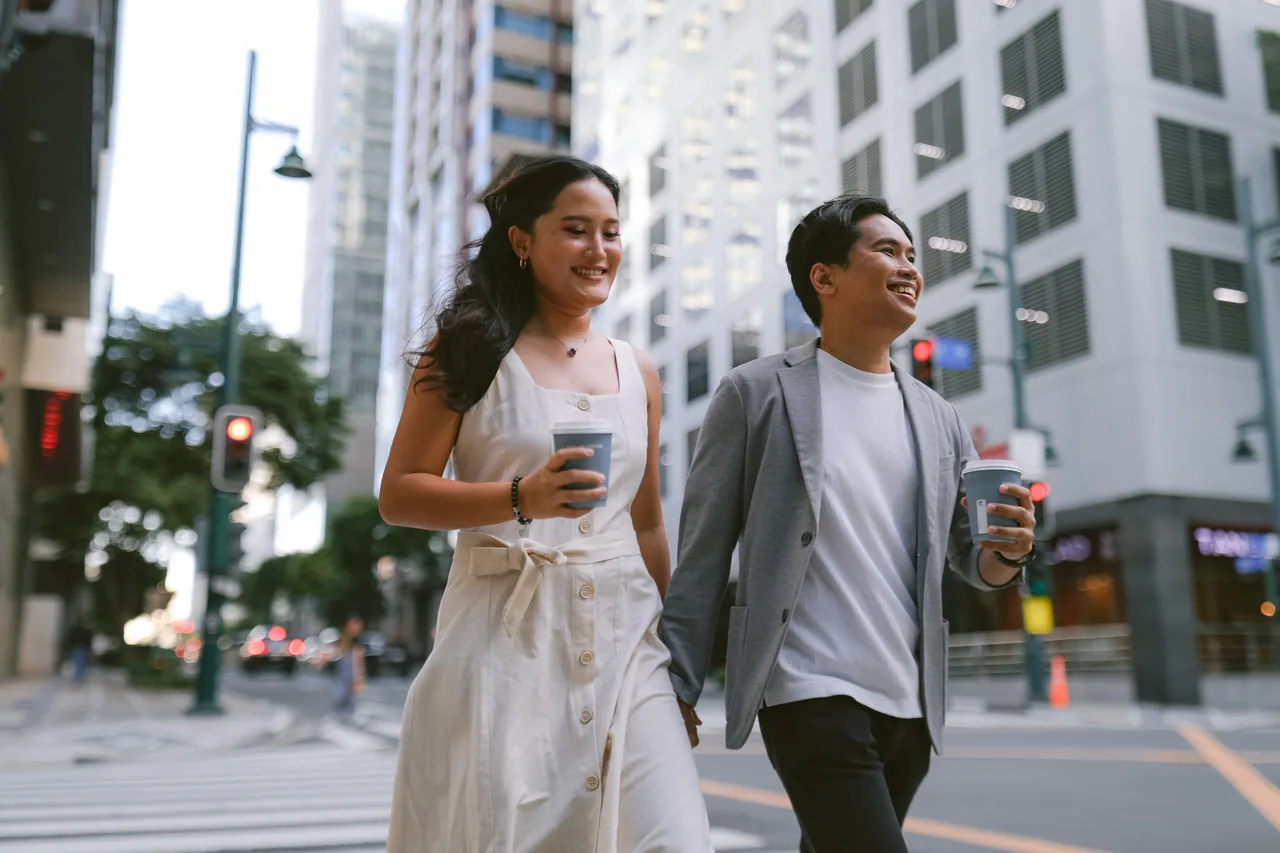 Stephen and Michelle walking hand in hand through the city with coffee