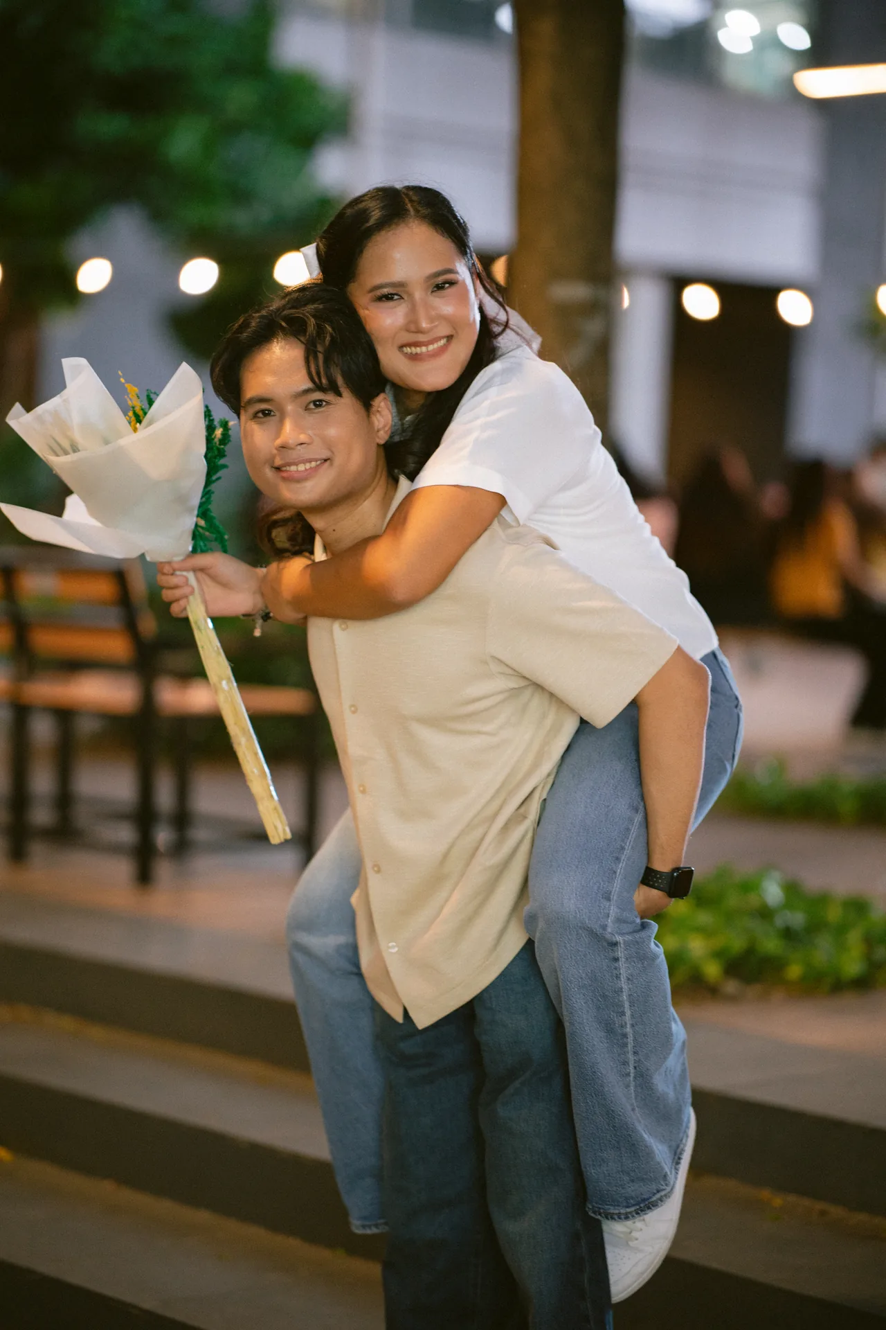 Stephen carrying a smiling Michelle on his back with a bouquet